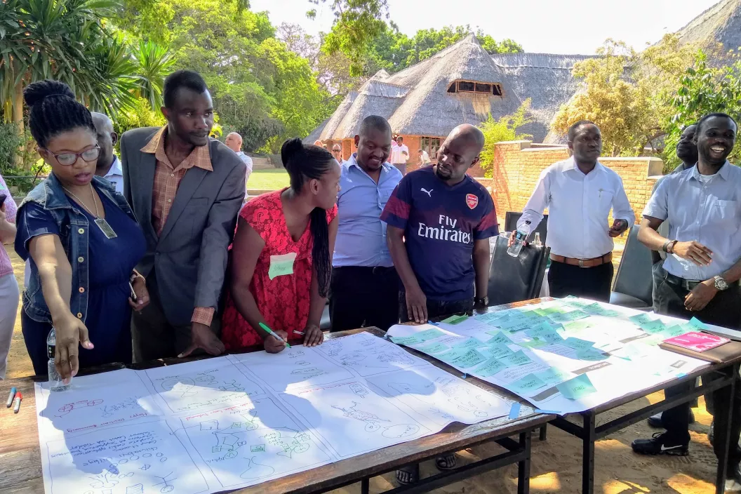 Photograph of an HCD workshop in Lilongwe, Malawi. Participants are presenting their ideas in storyboard form in an outdoors location. 